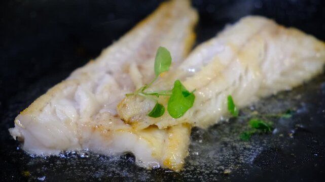 Indoor cooking scene: seasoned cod fillets are pan‑grilled in a cast‑iron skillet on a stovetop. Sizzle and texture of the fish as it cooks, highlighting the golden sear and aromatic seasoning. 