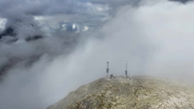 Aerial view of the communication towers on the rocky summit of Trollstigen surrounded by thick clouds in Andalsnes, More og Romsdal, Norway.