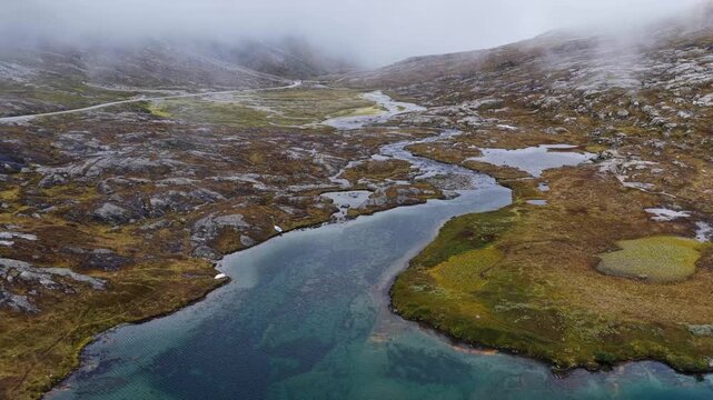 Aerial view of Alnesvannet lake surrounded by rocky mountain terrain and mist in the Trollstigen area of Andalsnes, More og Romsdal, Norway.