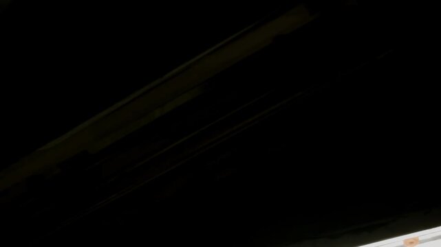 Close-up of fluorescent tube lights with a natural defect, showing subtle color shifts and dimming. The detailed texture and atmospheric lighting suggest an aged or industrial setting..