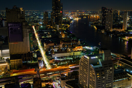 Bangkok, Thailand - 20 November 2025: View of the illuminated Bangkok skyline at night featuring skyscrapers, the Chao Phraya River, and traditional temple architecture.