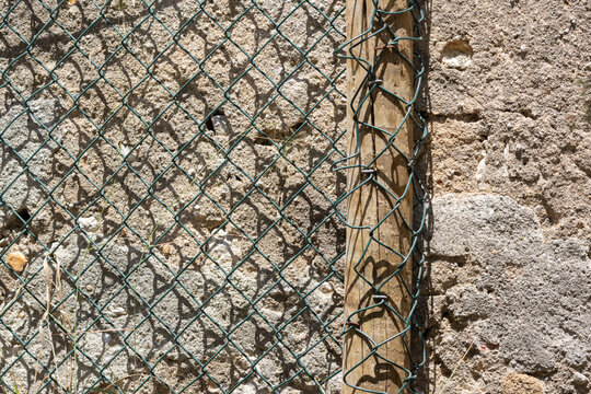 Chain link fence creating shadow pattern on stone wall