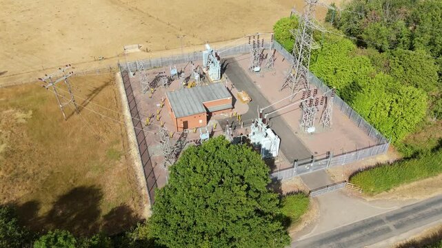 Aerial view of the Bourne West NGED 132kV Substation featuring electrical transformers, power lines, and metal fencing in Bourne, England, United Kingdom.