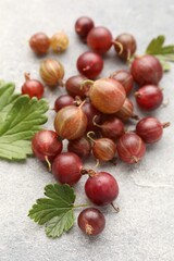 Fresh red gooseberries and green leaves on grey table, closeup © New Africa