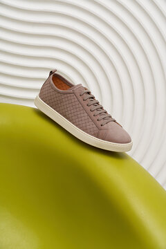 Stylish brown sneaker resting on curved green surface