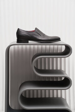Stylish black shoe displayed on modern gray shelf