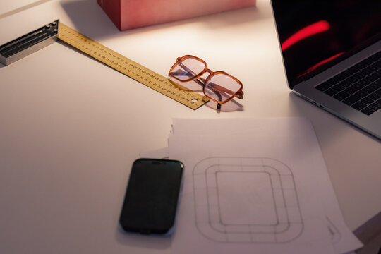 Sketches, glasses and devices on table at office