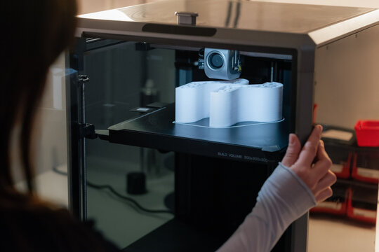 Person Using a 3D Printer to Create a White Object