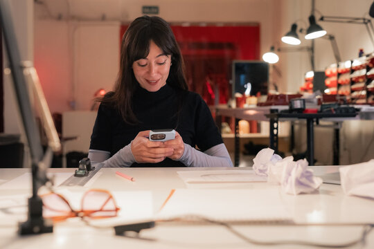 Smiling woman using smartphone for communication at work