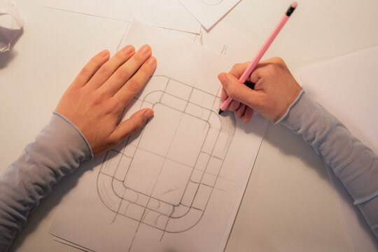 Woman drawing sketch of new product using pencil and paper