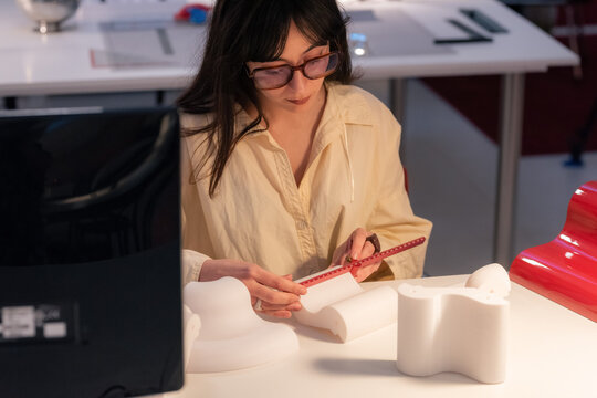 Woman Designs a Model While Measuring Materials at a Workshop