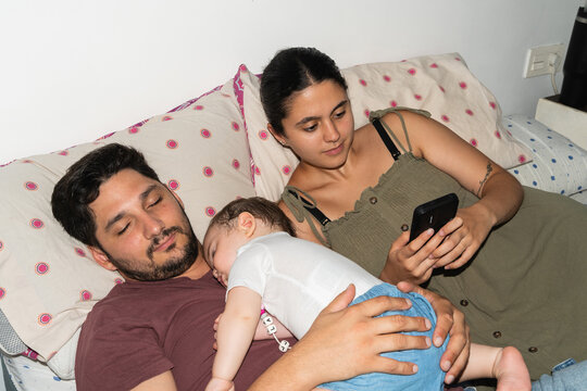 A family relaxing in bed at home. Father and daughter are sleeping