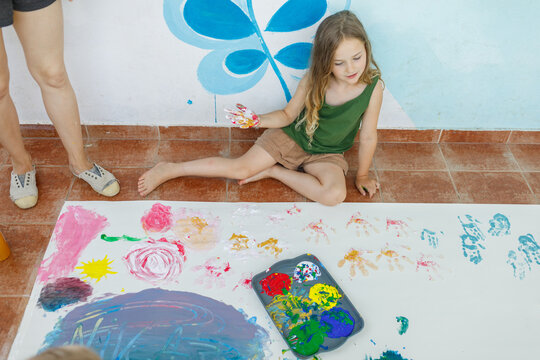 Child and mom enjoy finger painting with colored tempera 