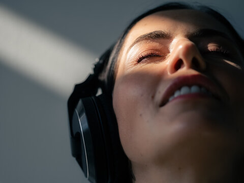 Smiling woman enjoying listening music in headphones in sunlight