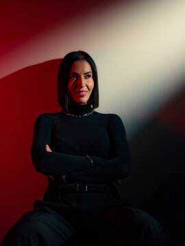 Confident woman posing at studio in beam light