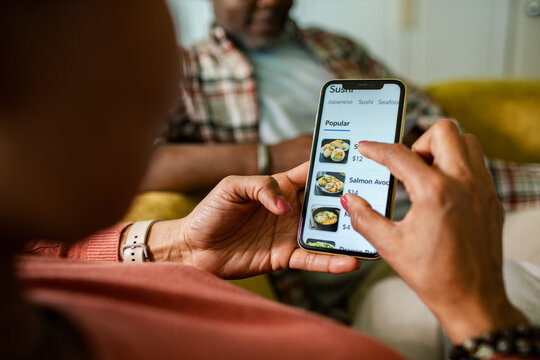 Woman ordering sushi on smartphone at home