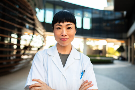 Confident female doctor standing outside modern hospital