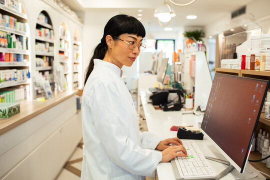 Female pharmacist working on computer in modern pharmacy