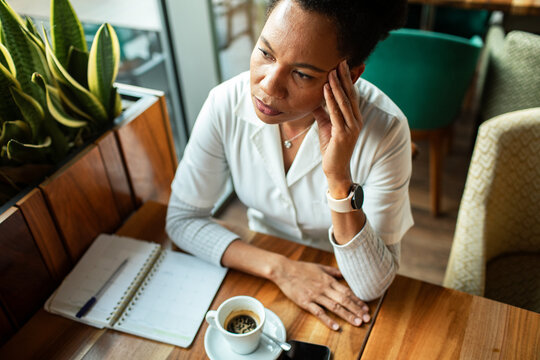 Thoughtful woman planning schedule at cafe table