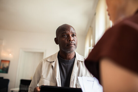 Mature man listening to caregiver during home visit