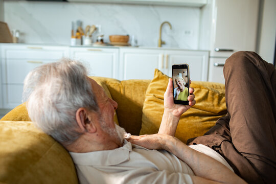Relaxed senior man video chatting on smartphone at home