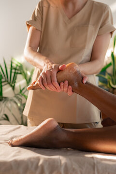 Professional therapist giving foot massage to woman