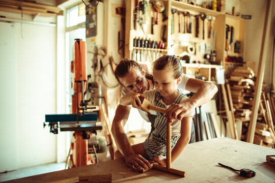 Father teaching daughter woodworking in home workshop
