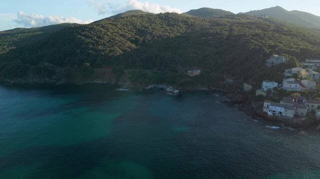 Marine de Meria Corsica drone panning shot sunset bay white yacht Genoese tower coastal village crescent beach landscape, left to right pan in golden hour light Cap Corse Cinematic 4K aerial drone 