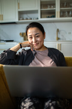 Smiling woman using laptop at home kitchen