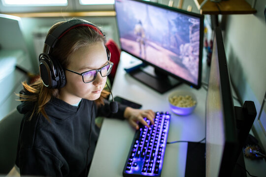 Teen girl gamer using pc with headset at home
