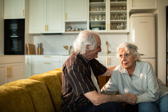 Senior couple having a heartfelt conversation on sofa in home kitchen