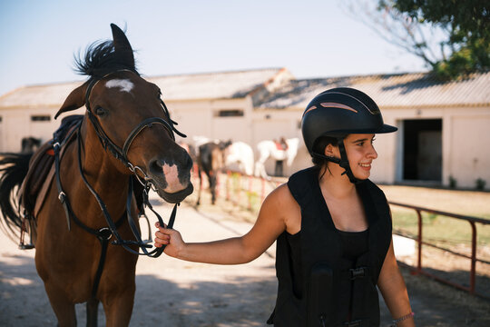 Horsewoman leading horse out of stable: equestrian lifestyle