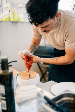 Chef Prepares Sauce in Small Cups at Outdoor Kitchen