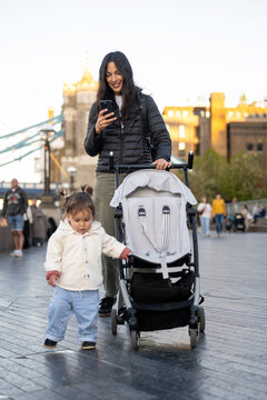 Mother Checking Smartphone While Walking With Baby 