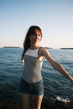 Woman enjoying the sea breeze on rocky coast