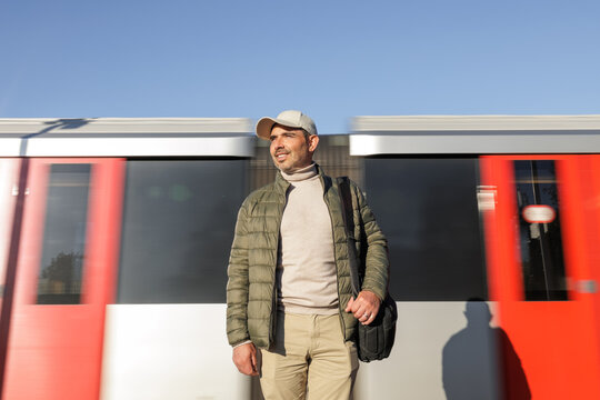 Happy man standing next to a moving outdoor train