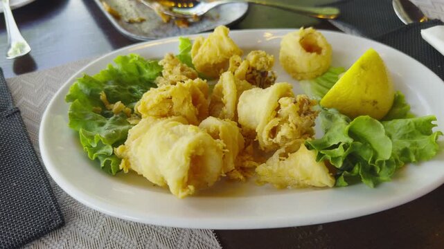 Fried Calamari Rings Served With Fresh Lemon Slice And Lettuce Leaves. Seafood Meal Dish