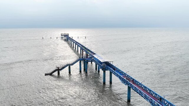 Aerial view of the blue BD Navy Jetty extending into the sea with calm waters under a cloudy sky in Cox's Bazar District, Chittagong Division, Bangladesh.