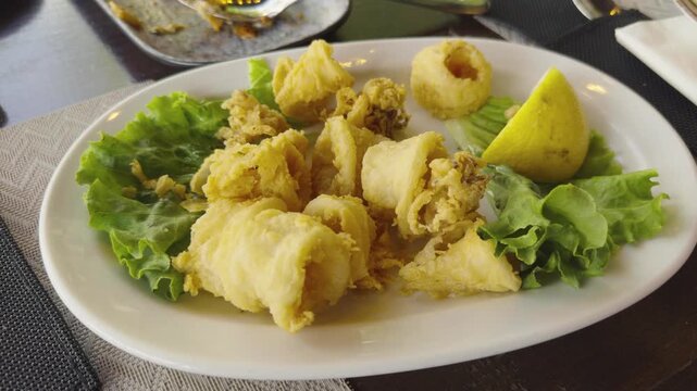 Crispy Deep Fried Calamari Squid Rings Served With Green Lettuce Leaves And Lemon Wedge. Mediterranean Cuisine 