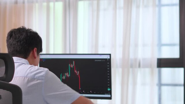 male trader throwing headphones in frustration and despair after witnessing a massive stock market crash on computer monitor candlestick chart