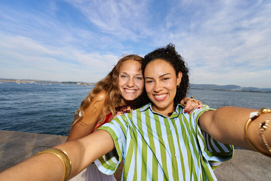 Happy women friends taking selfie by the sea
