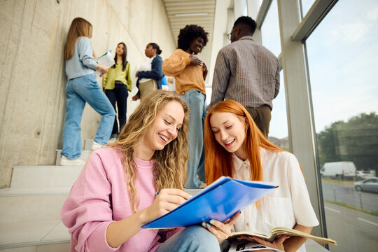 Classmates discuss their research sitting on the stairs