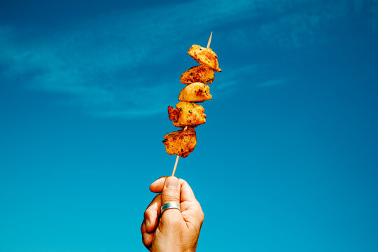 from a low angle, a man raises a spanish pincho moruno