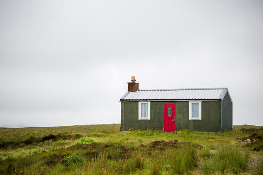 Tiny croft house with a red door.