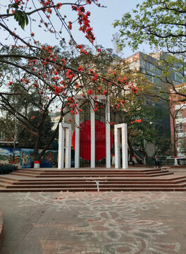 Sohid Minar Modern minimalist pillars with red accents in urban park setting during autumn.