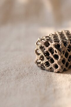 Close-up of a 3D printed porous metal lattice structure resting on textured linen fabric