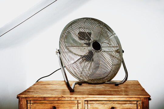 Fan Placed on Wooden Dresser in a Simple Indoor Setting
