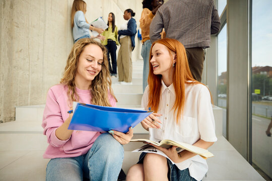 Young women discuss their studies sitting on the stairs