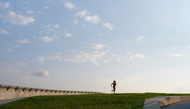 Runner crossing grassy hill at sunrise
