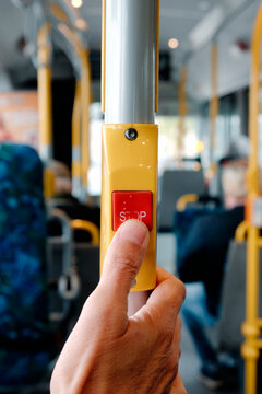 a close-up of a man pressing the red stop-request button on a bus